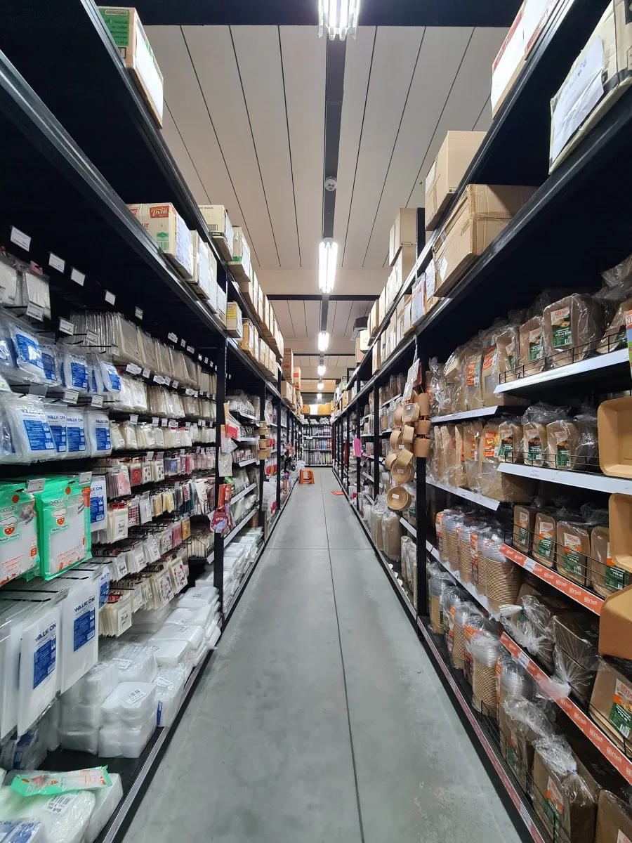 Wide store aisle stocked with paper packaging, plastic packaging, bags, and cups